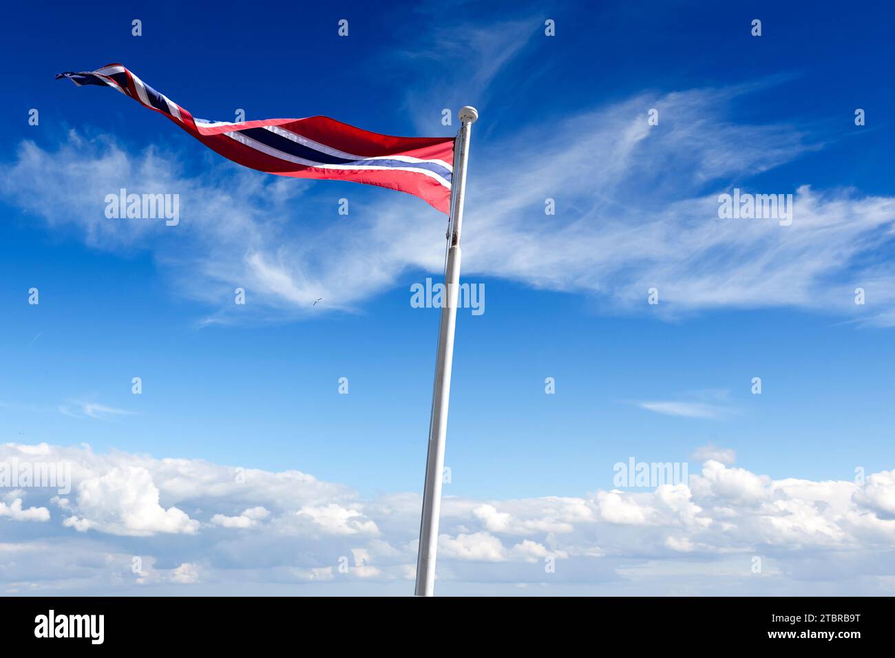 Bandiera norvegese davanti al cielo blu con nuvole bianche Foto Stock