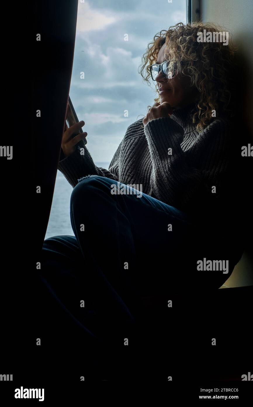 Una donna si siede e si rilassa usando il collegamento del telefono cellulare all'interno della cabina, crociera in traghetto, godendo di viaggio e trasporto. Passeggero e wifi smartphone wireless wifi. Persone che si rilassano per piacere Foto Stock