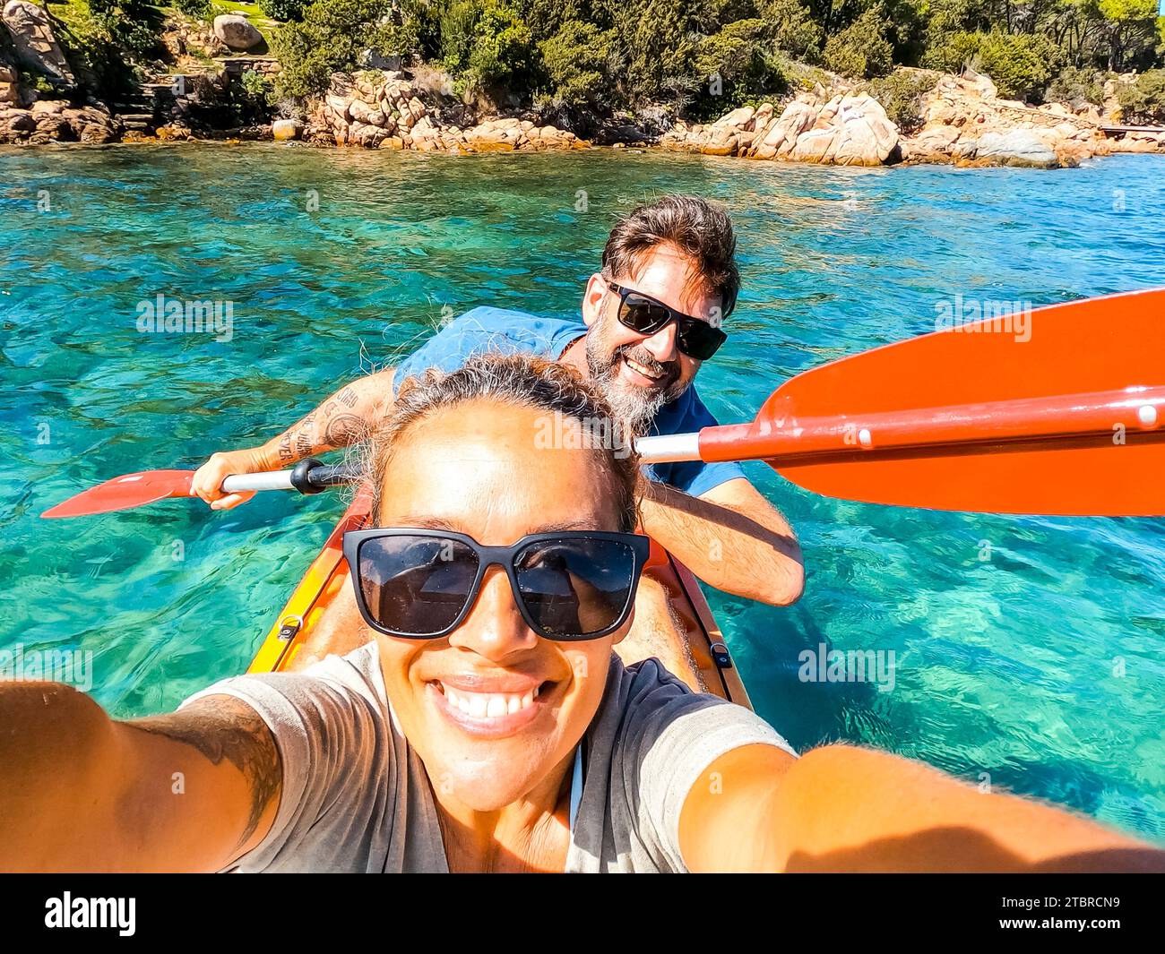 Felice coppia adulta attiva che partecipa a un'escursione in canoa in kayak sulle acque cristalline del mare. Concetto di felicità uomo e donna nelle vacanze estive. Stile di vita sano. Turista Foto Stock