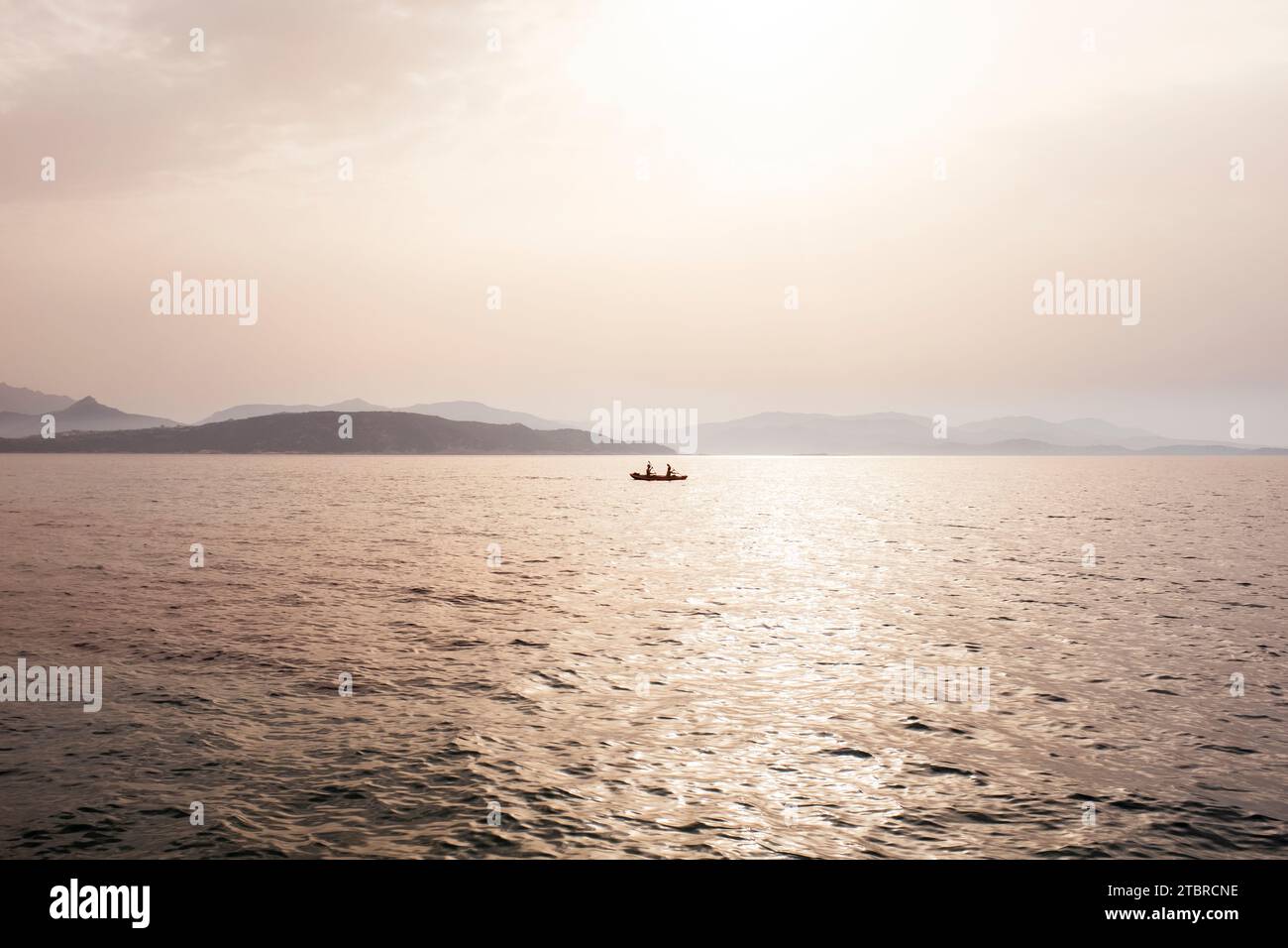 Paesaggio marino Misty Mood con barche da pescatori in mezzo al mare e costa sullo sfondo sotto la luce del sole nebbia. Foto Stock
