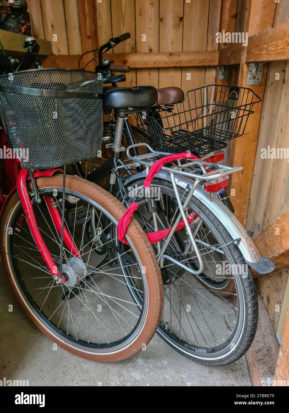 Biciclette custodite con una serratura per biciclette una accanto all'altra in un garage di legno nella località di Prerow, nella penisola di Fischland-Darß-Zingst, Meclemburgo-Pomerania occidentale, Germania Foto Stock