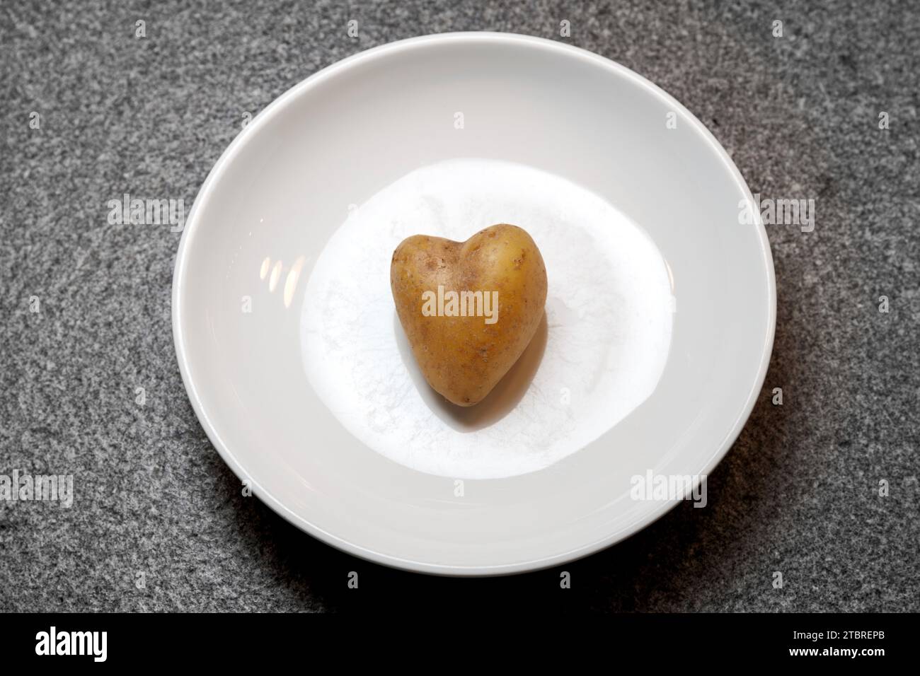 Patata a forma di cuore su un piatto bianco Foto Stock