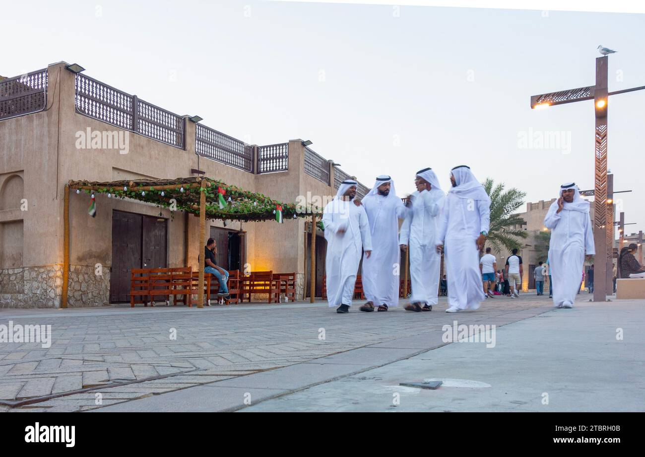 Piccolo gruppo di uomini degli Emirati passeggia attraverso il quartiere storico di al Shindagha al tramonto, Dubai, Emirati Arabi Uniti. Foto Stock