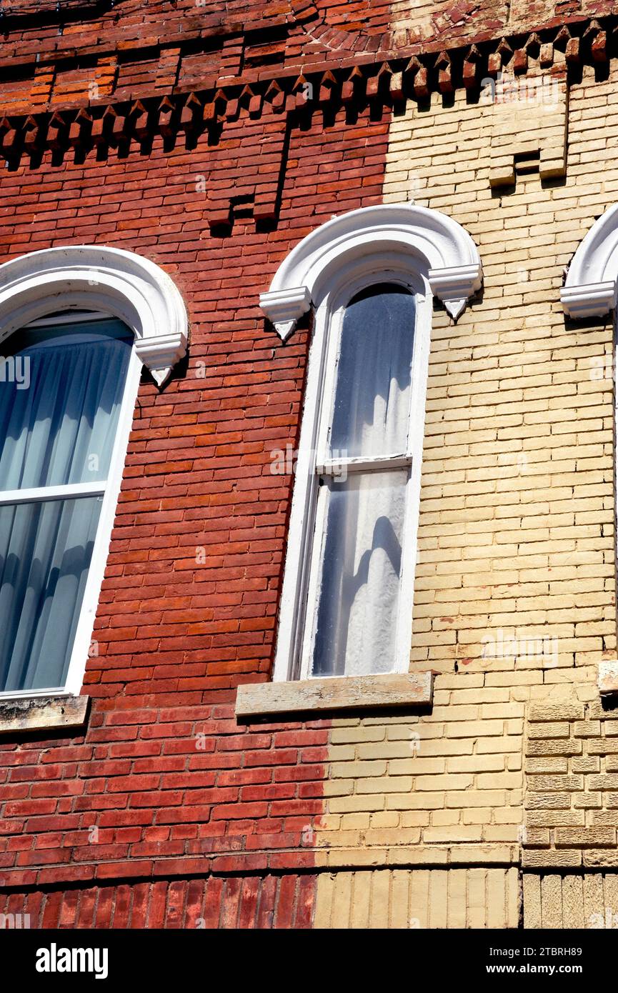 Il vecchio edificio in mattoni rossi e gialli ha finestre strette. Gli archi decorativi in legno sopra le finestre sono bianchi. L'edificio si trova a Counciil Grove, Kansas. Foto Stock