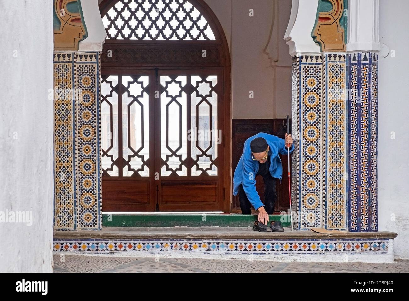 Anziano musulmano che rimette le scarpe quando lascia la grande Moschea / Jamaa el Kebir in medina della città di Tétouan / Tettawen, Marocco Foto Stock