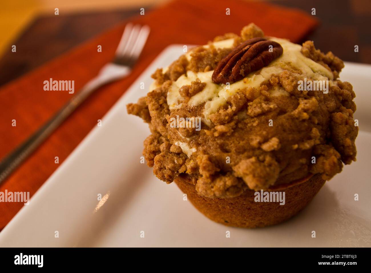 Vista ravvicinata del muffin frosted Gourmet Apple Cheesecake con pecan su piatto bianco Foto Stock