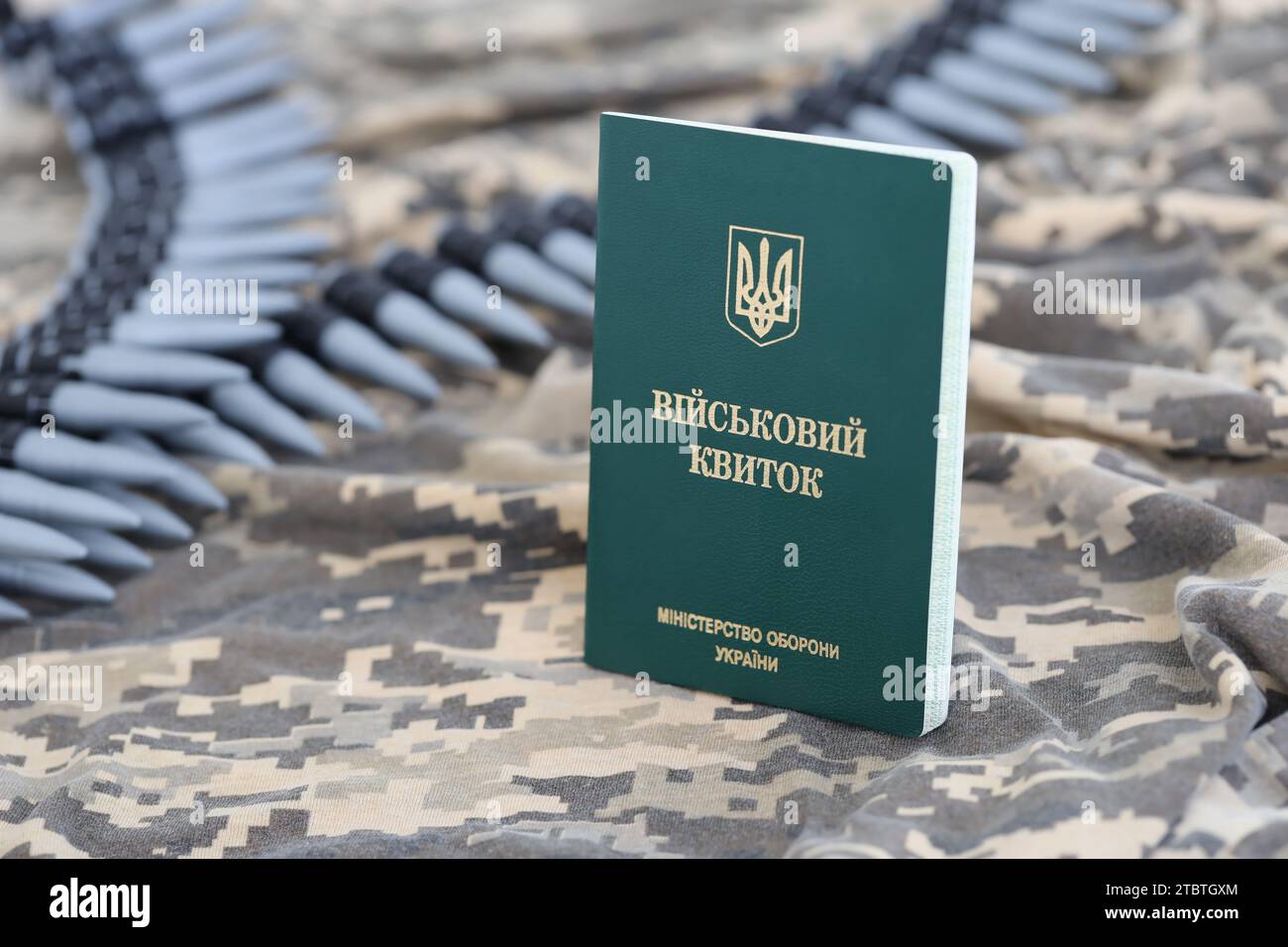 Documento d'identità militare ucraino su tessuto con trama mimetica pixeled. Panno con motivo camouflage in pixel grigio, marrone e verde con gettone personale dell'esercito ucraino e cintura di proiettili mitragliatrici Foto Stock