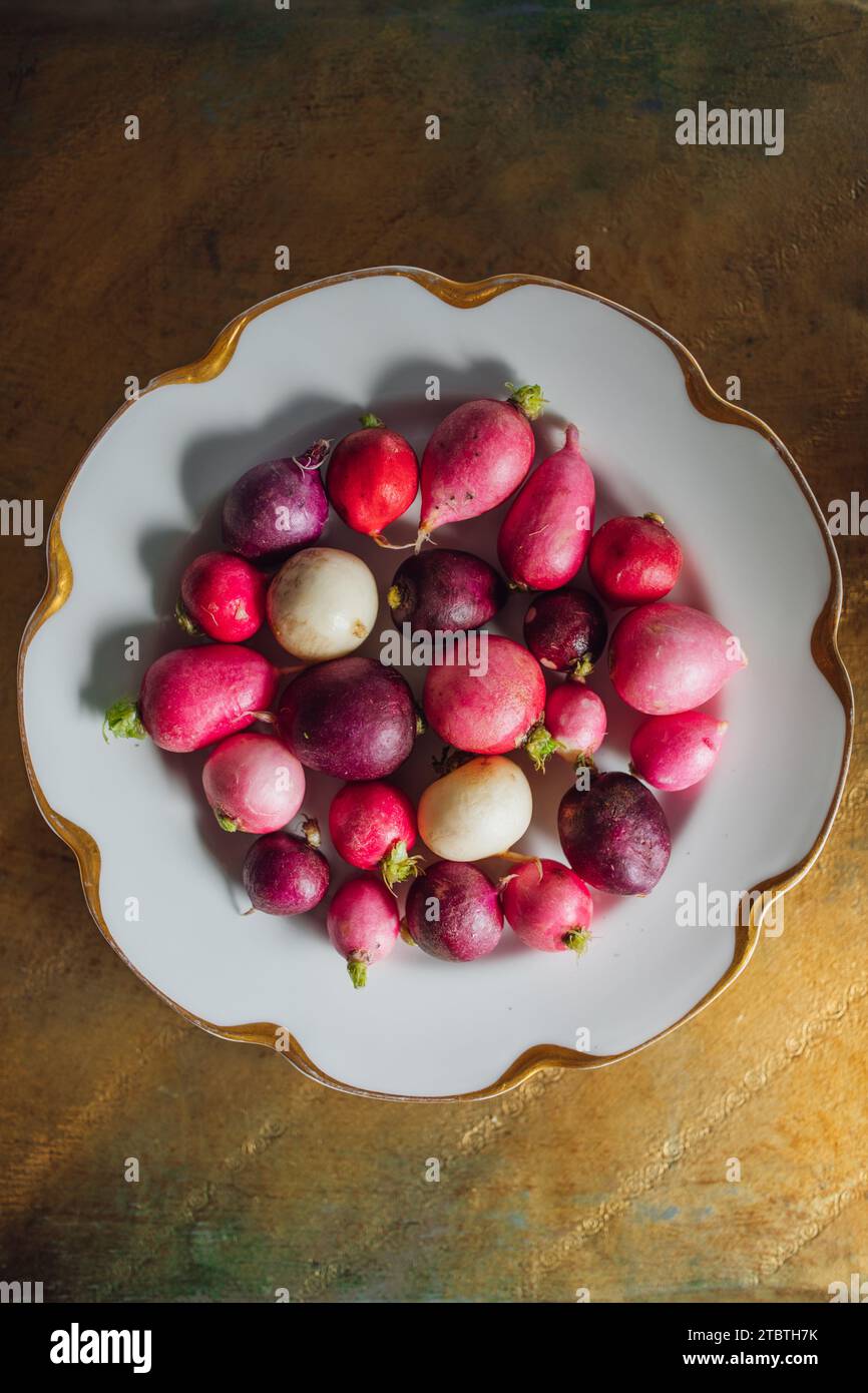 un assortimento di sfumature rosa, rosse, viola e bianche su lastra bianca con bordo smerlato oro Foto Stock