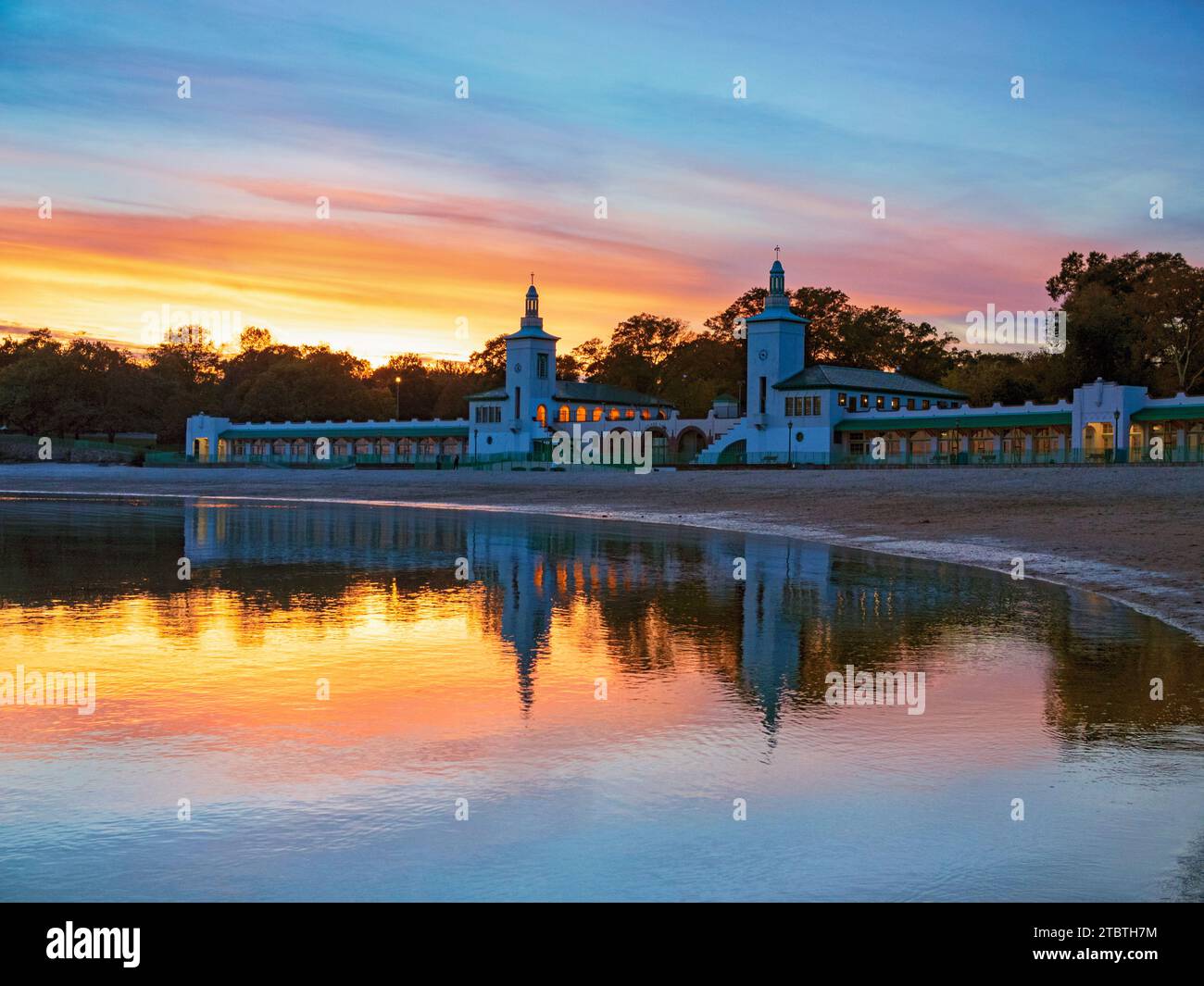 Rye Playland Beach, ora d'oro dopo il tramonto, nell'acqua blu autunnale, nel cielo arancione a contrasto e nei riflessi colorati dell'acqua, New York Foto Stock