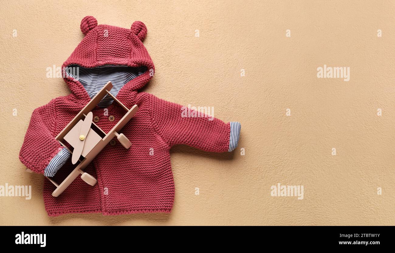 Elegante pullover per bambini e giocattolo aereo su sfondo beige con spazio per il testo Foto Stock