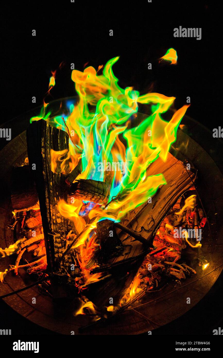 Flames multicolore che ballano in Metal Fire Pit di notte Foto Stock
