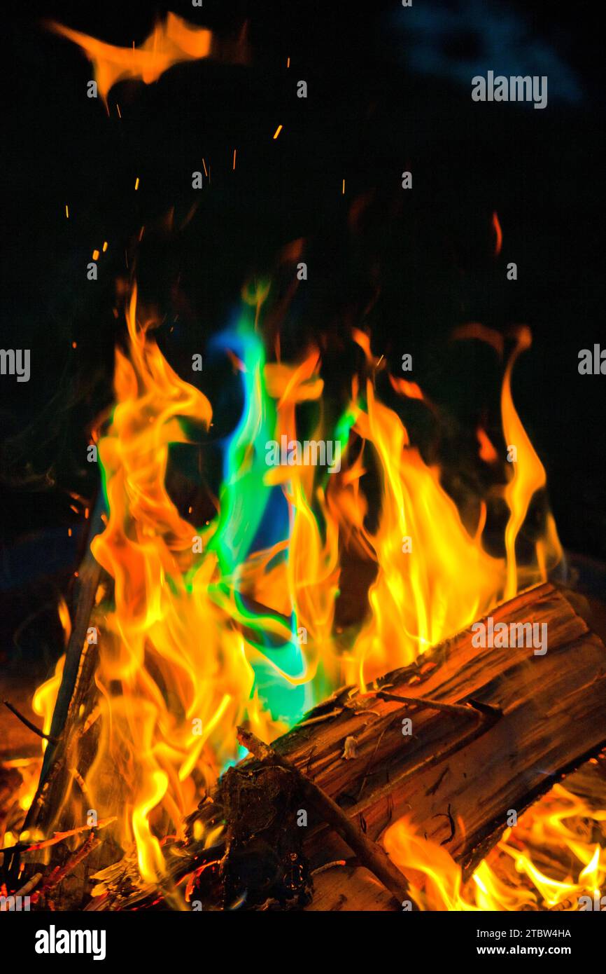 Vibrante spettro di fiamme nel fuoco a legna di notte con riflessi blu-verdi Foto Stock