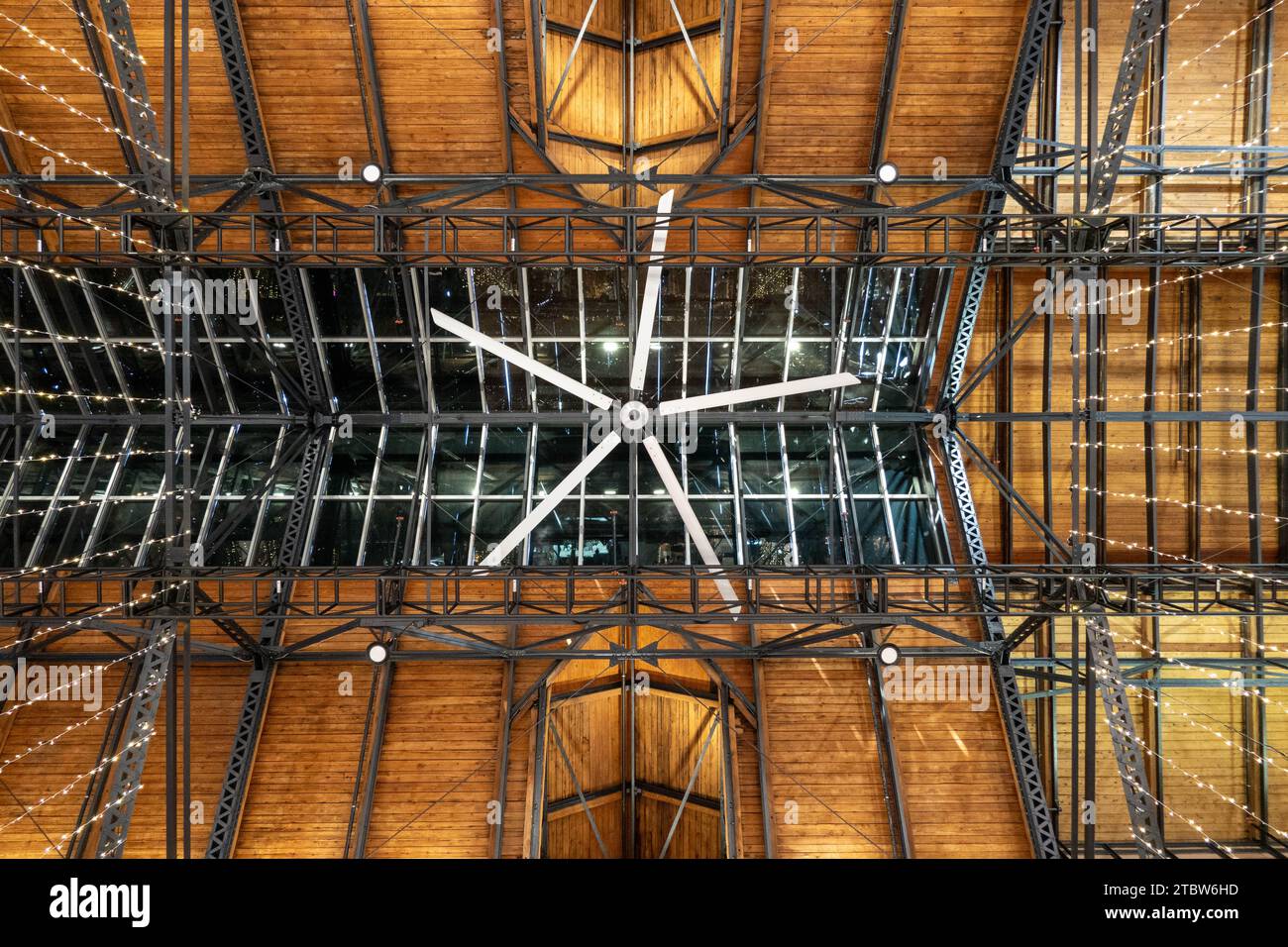 Soffitto in legno con grande ventilatore a soffitto e elementi strutturali grigi rubati con luci per le vacanze sospese. Foto Stock