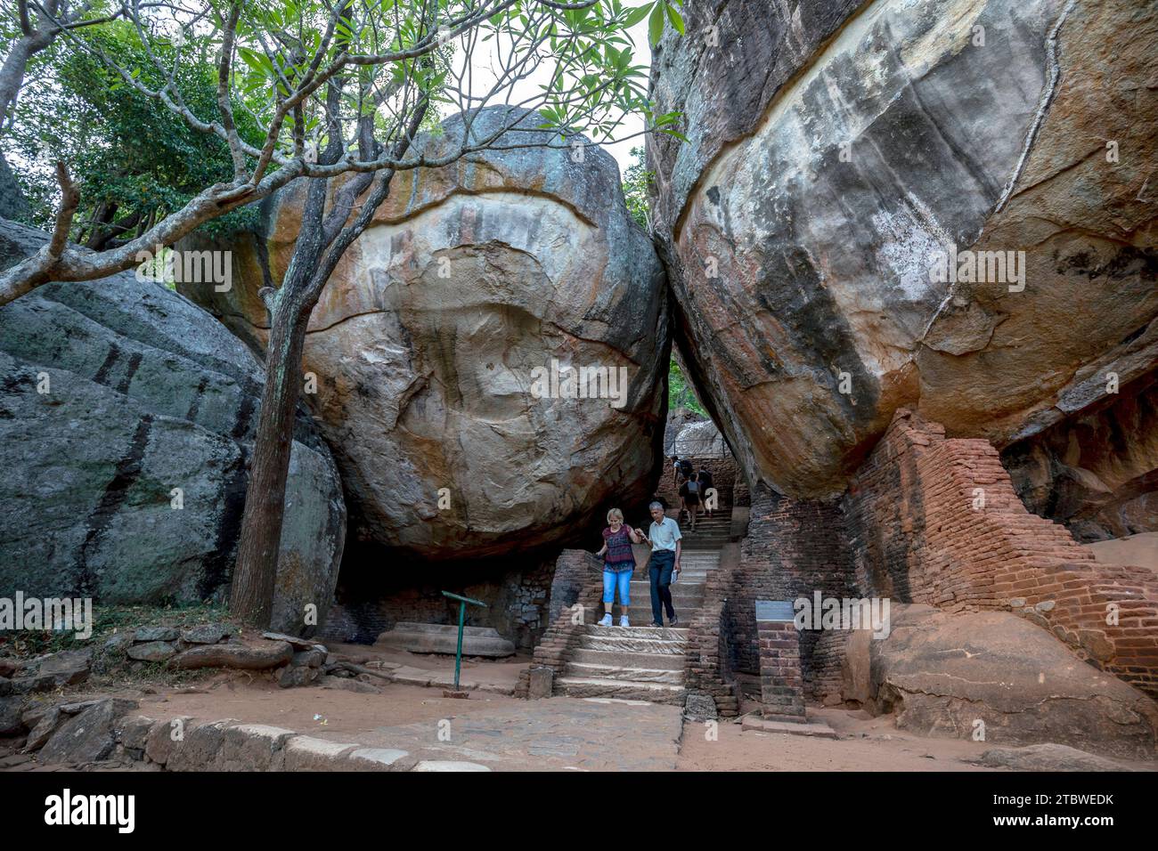 I visitatori della fortezza di Sigiriya Rock in Sri Lanka passano attraverso l'arco di Boulder numero uno. Questo faceva parte dell'antico sentiero fino alla cima delle rocce. Foto Stock