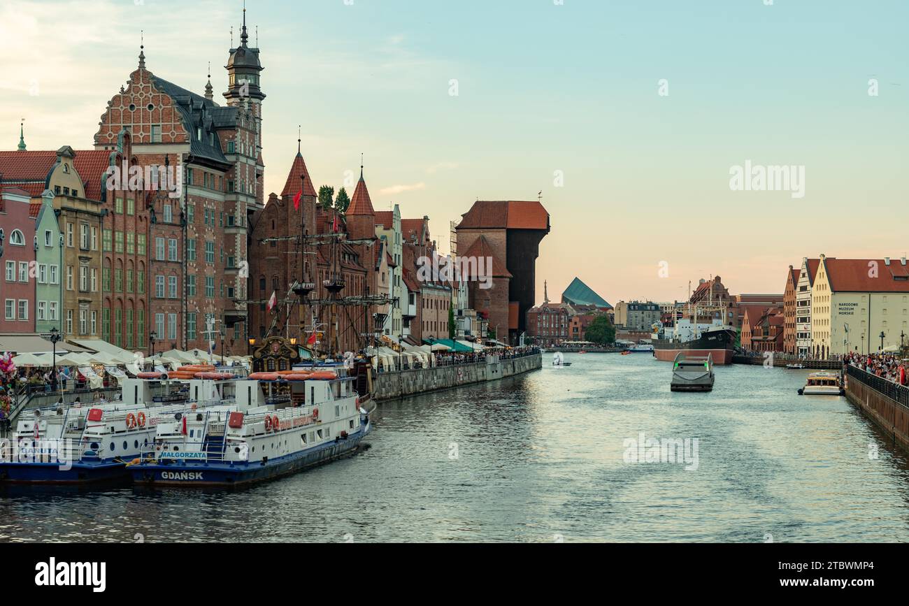 Una foto di alcuni punti di riferimento di Danzica vicino al fiume Motlawa, come la gru, il St Mary's Gate e la nave Black Pearl, al tramonto Foto Stock