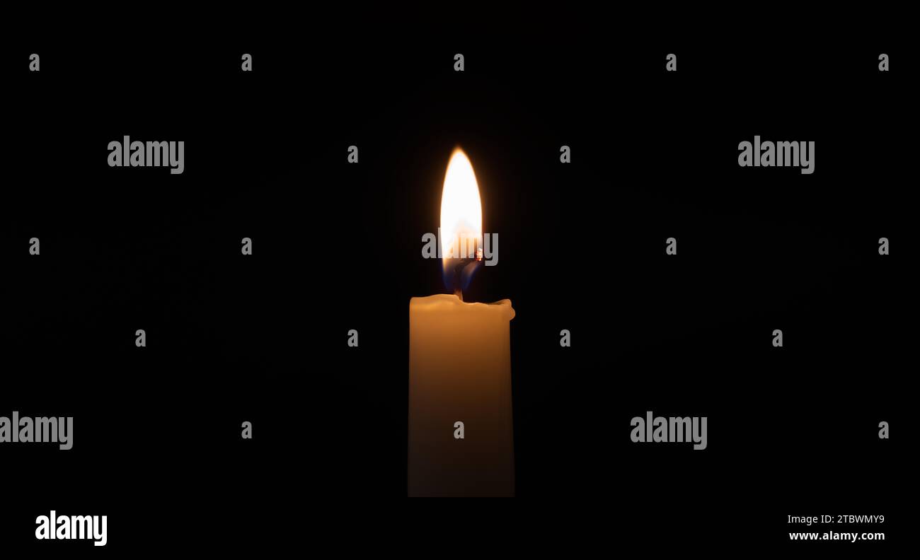 Primo piano di una fiamma di candela nell'oscurità con spazio di copia libero Foto Stock