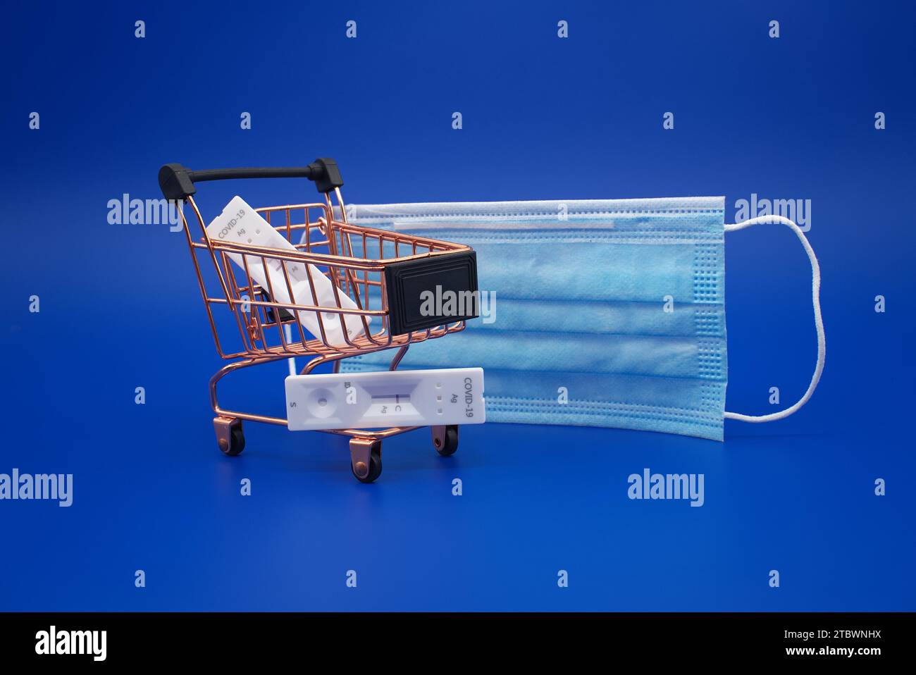 Covid-19 e coronavirus concetto sanitario con maschera, carrello e kit di test rapido anticorpi su sfondo blu Foto Stock