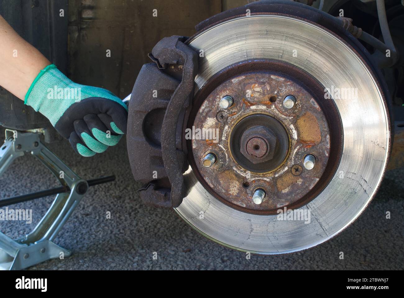 Servizio di sostituzione delle pastiglie dei freni a disco per auto con la mano del meccanico, rotore dei dischi dei freni senza ruote Foto Stock