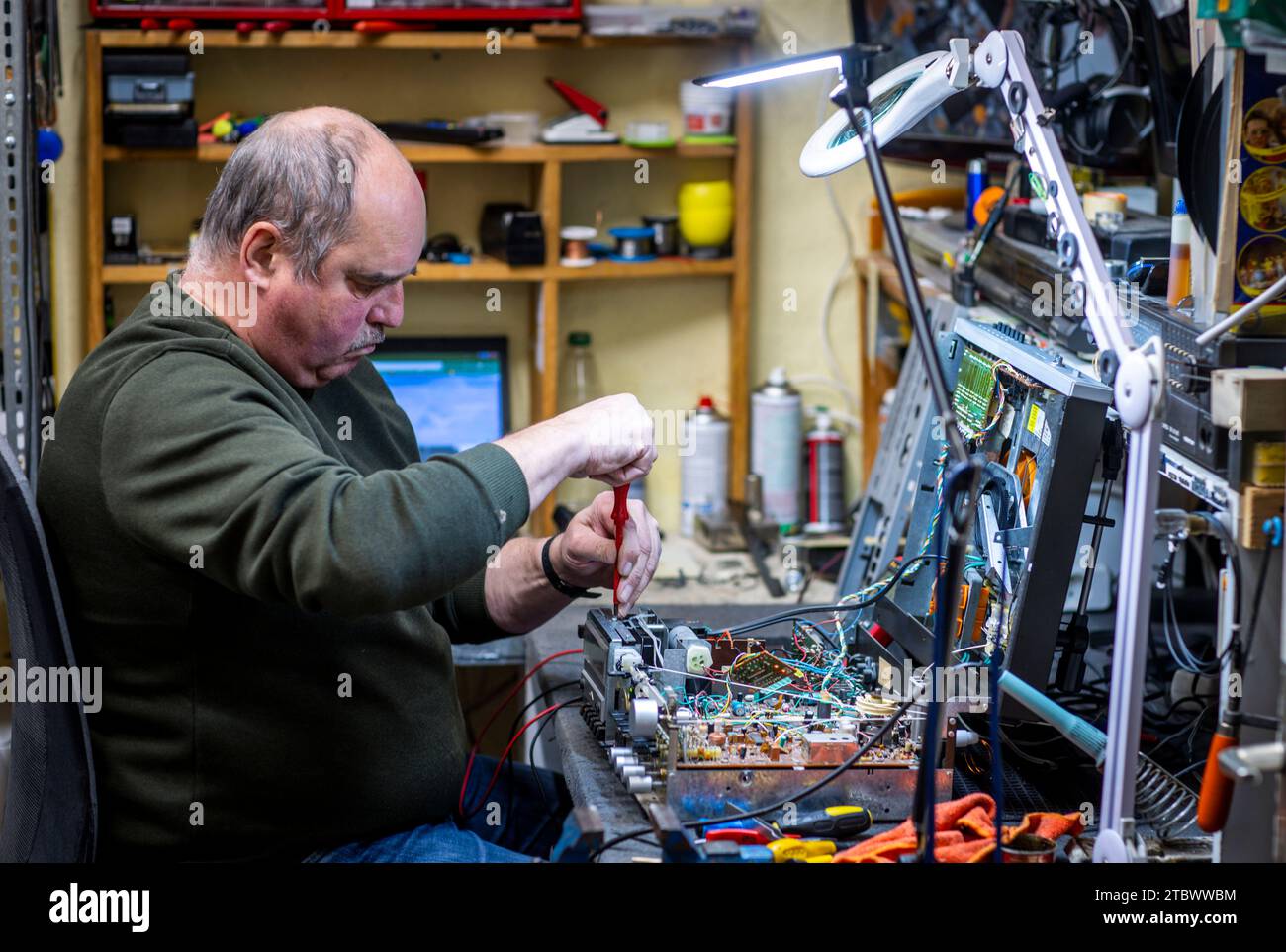 Schwerin, Germania. 28 novembre 2023. Jens-Uwe Peters ripara vecchie radio, lettori di dischi e sistemi hi-fi nella sua piccola officina. I piccoli elettrodomestici provenienti da est e ovest sono stati ripristinati al loro funzionamento per circa 34 anni. I clienti abituali con un debole per la tecnologia radio GDR, in particolare, consegnano i loro dispositivi al tecnico radio e televisivo addestrato. La mancanza di ricambi e il calo di interesse tra i clienti più giovani fanno sì che i giorni di questa officina unica siano probabilmente numerati. Credito: Jens Büttner/dpa/Alamy Live News Foto Stock