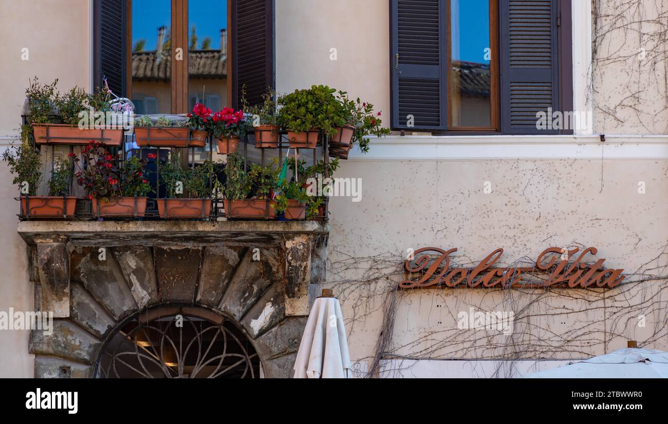Una foto di un balcone pieno di piante a Roma accanto al segno della famosa espressione italiana Dolce vita Foto Stock