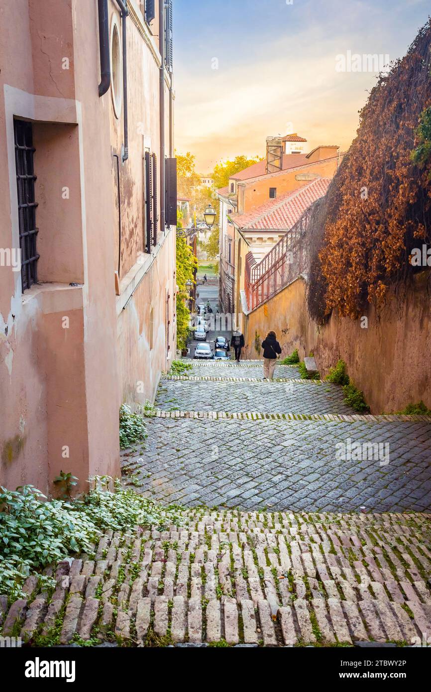Stradina stretta di Roma con i turisti al tramonto in estate Foto Stock