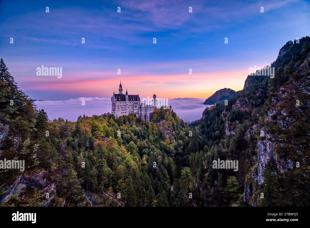 Il castello di Neuschwanstein, visto dal ponte Marienbrücke all'alba in autunno, che si innalza dalla nebbia. Foto Stock