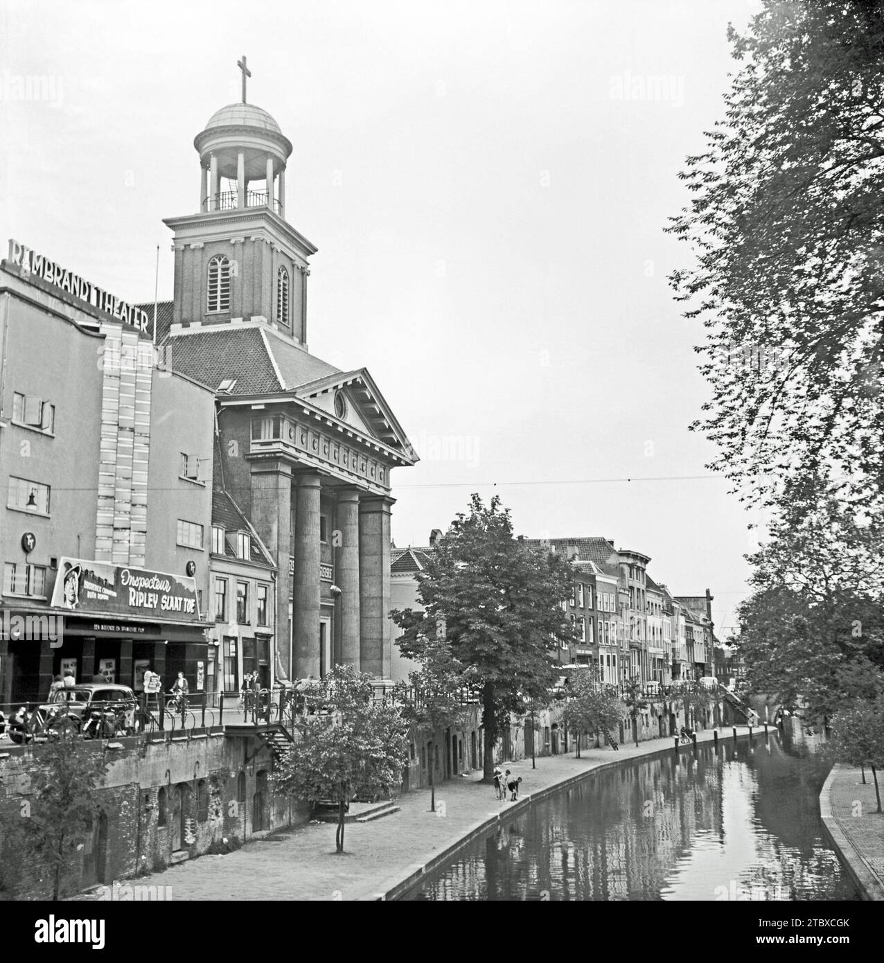 Utrecht, Paesi Bassi nel 1955 – al Viebrug guardando a nord lungo la strada sopraelevata (Oudegracht) accanto all'Oudegracht, o "vecchio canale", che attraversa la città. Il Rembrandt Theater (a sinistra) è stato aperto nel 1913. Nel 1933 è stato trasformato in un cinema in stile Art Deco. Nel 1955 è stato proiettato "Inspecteur Ripley Slaat Toe", uscito negli Stati Uniti nel 1954 con il titolo "Down Three Dark Streets", un film noir americano con Broderick Crawford e Ruth Roman. Accanto al cinema si trova la chiesa di Sant'Agostino, una fotografia d'epoca degli anni '1950. Foto Stock