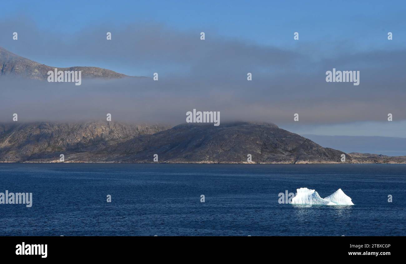 un iceberg, basse nuvole e colline, vicino al nanortalik vicino al fiordo di tasermiut nella groenlandia meridionale, su una nave da crociera in estate Foto Stock