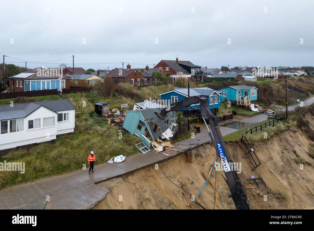 Gli operai demolitori abbattono la prima di cinque case sulla scogliera nel villaggio di Hemsby, che è stato colpito dall'erosione costiera. L'alta marea e i forti venti hanno causato il crollo di un tratto di strada privata ad Hemsby, nel Norfolk, il mese scorso. Data immagine: Sabato 9 dicembre 2023. Foto Stock