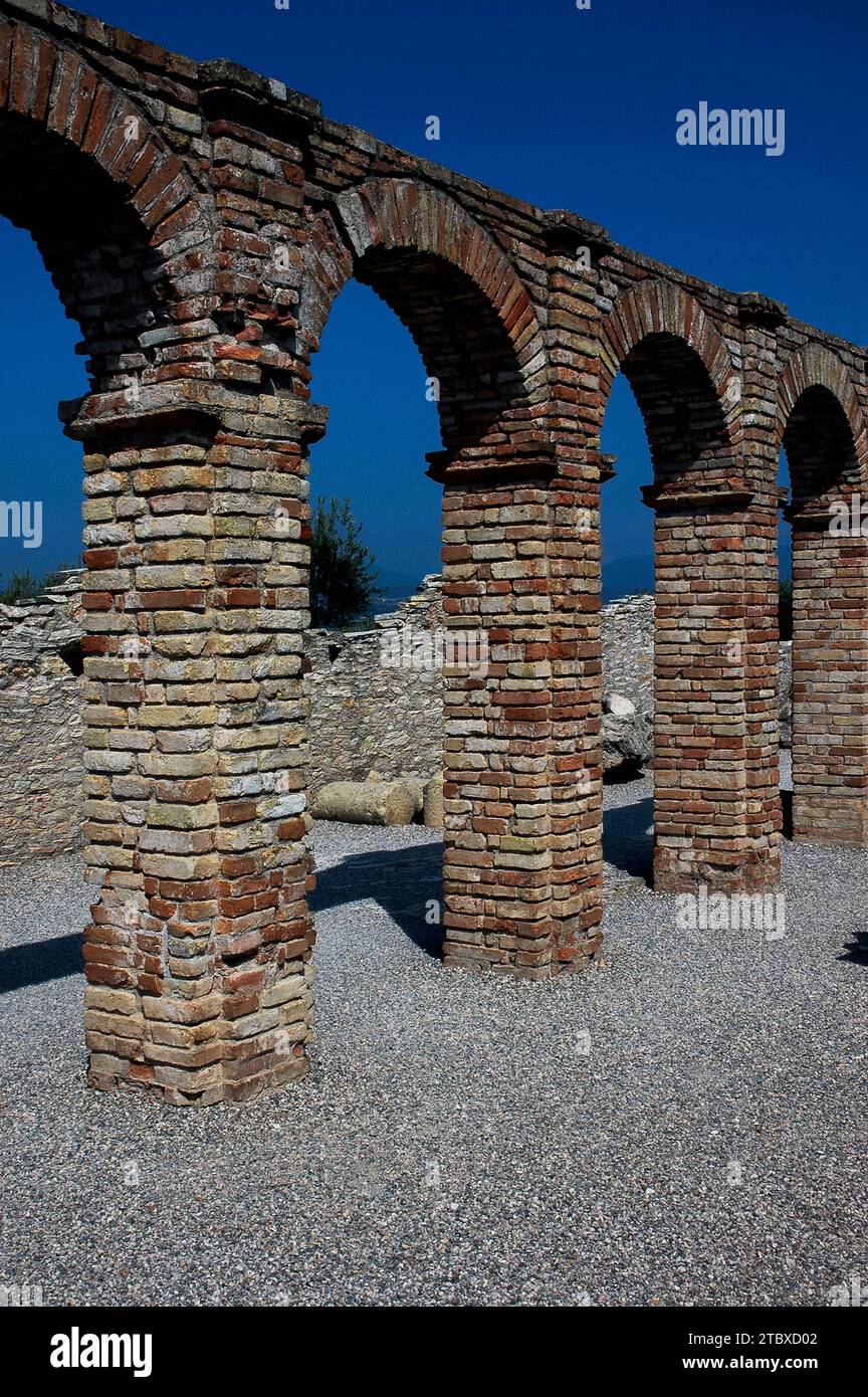 Linea di archi romani in mattoni alle Grotte di Catullo, una vasta villa romana costruita tra la fine del i secolo a.C. e il II secolo d.C., a Sirmione sul Lago di Garda in Lombardia. La villa è stata saccheggiata per i materiali da costruzione ed è ora una rovina. Foto Stock