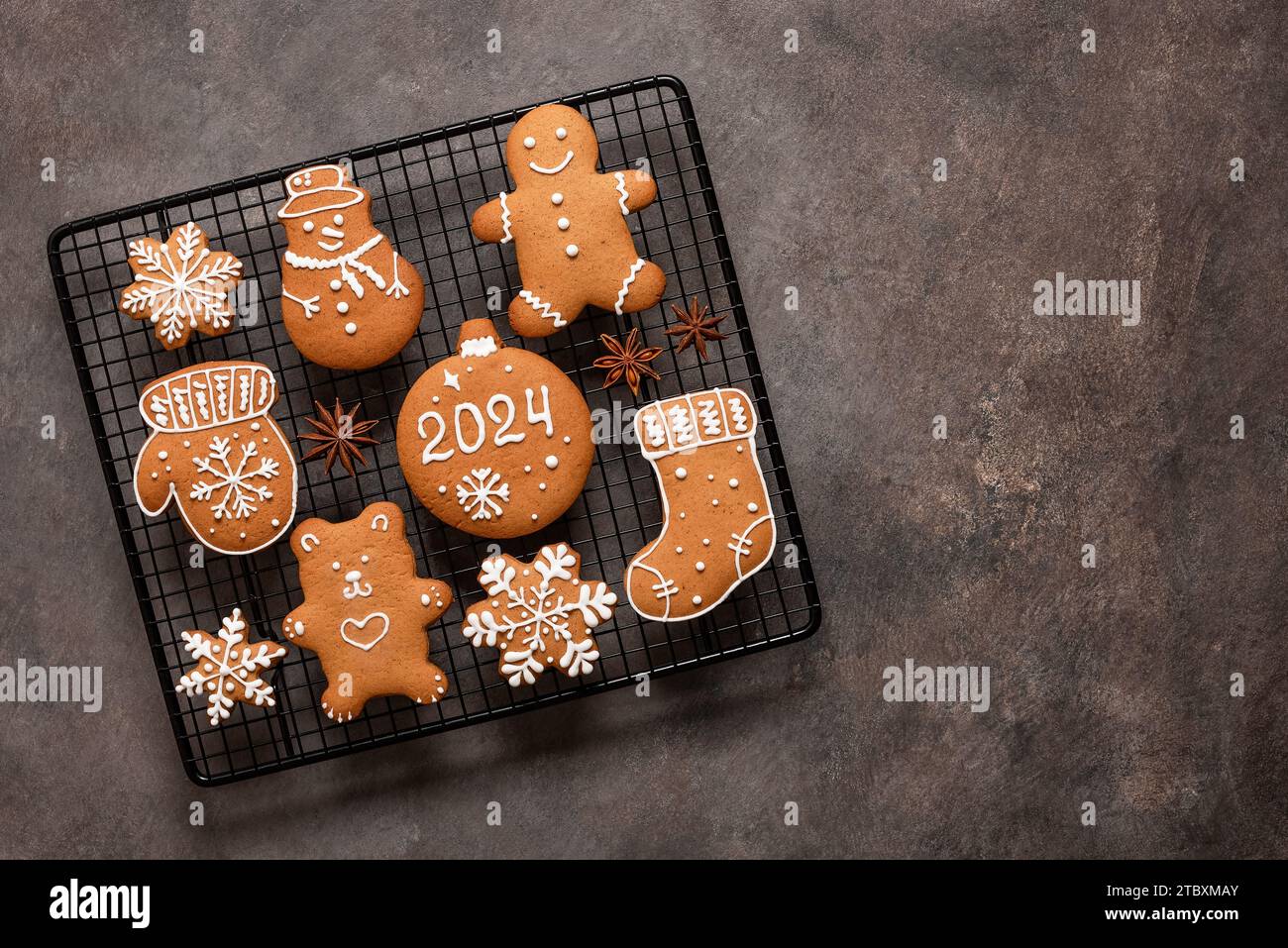 Set di biscotti natalizi al pan di zenzero su una griglia rinfrescante, sfondo rustico marrone. Vista dall'alto, base piatta, spazio di copia. Foto Stock