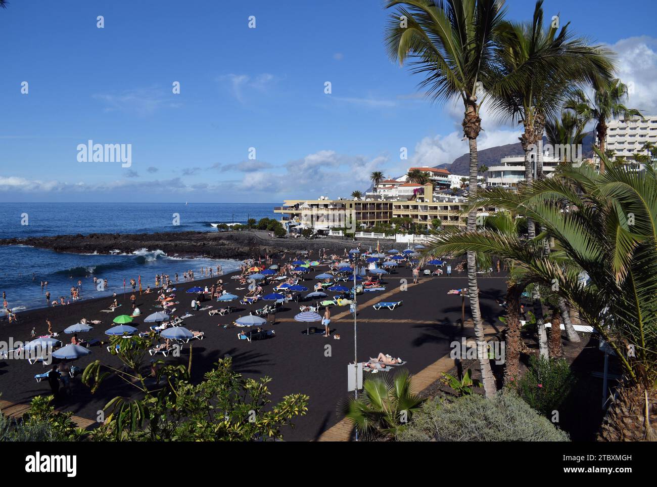 La spiaggia di sabbia nera vulcanica di la Arena a Tenerife, nelle Isole Canarie, piena di turisti. Foto Stock