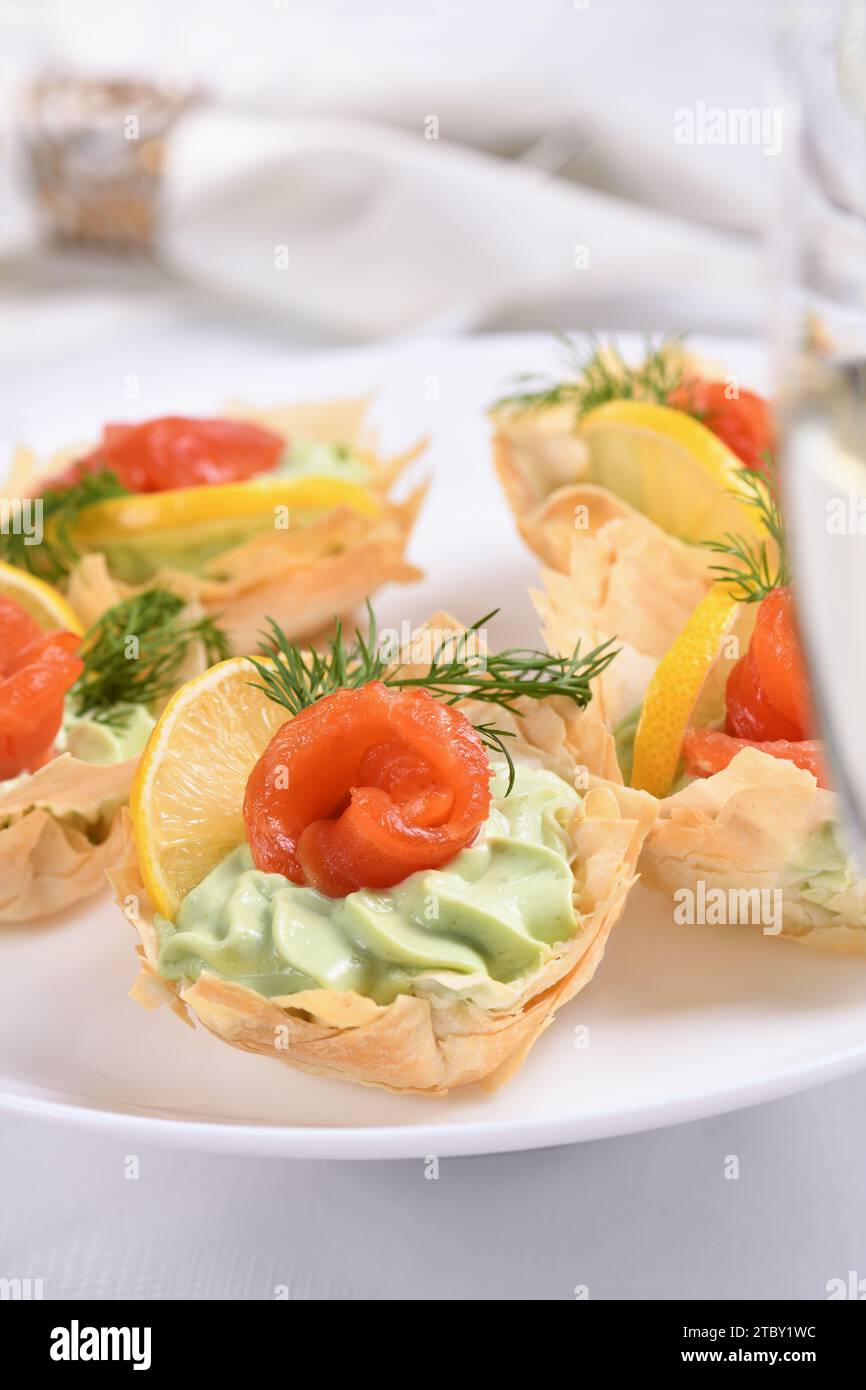 Avocado montato con crema di formaggio soffice nella mousse più delicata, una fetta di salmone e limone. Servita in cesti croccanti con pasta phyllo cotta al forno Foto Stock