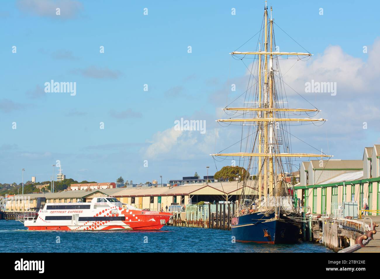 Il Rottnest Express Ferry arriva all'ormeggio dietro la nave da addestramento Leeuwin II a Fremantle Harbour, Perth, Australia Occidentale. Foto Stock