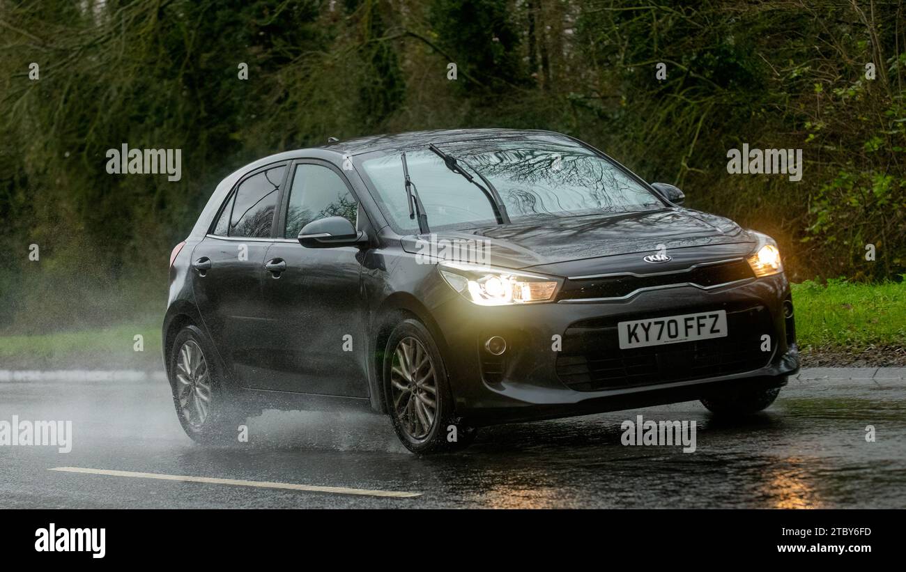 Milton Keynes,Bucks,UK - 9 dicembre 2023: 2020 Kia Rio guida su una strada bagnata, sotto la pioggia con i fari accesi Foto Stock