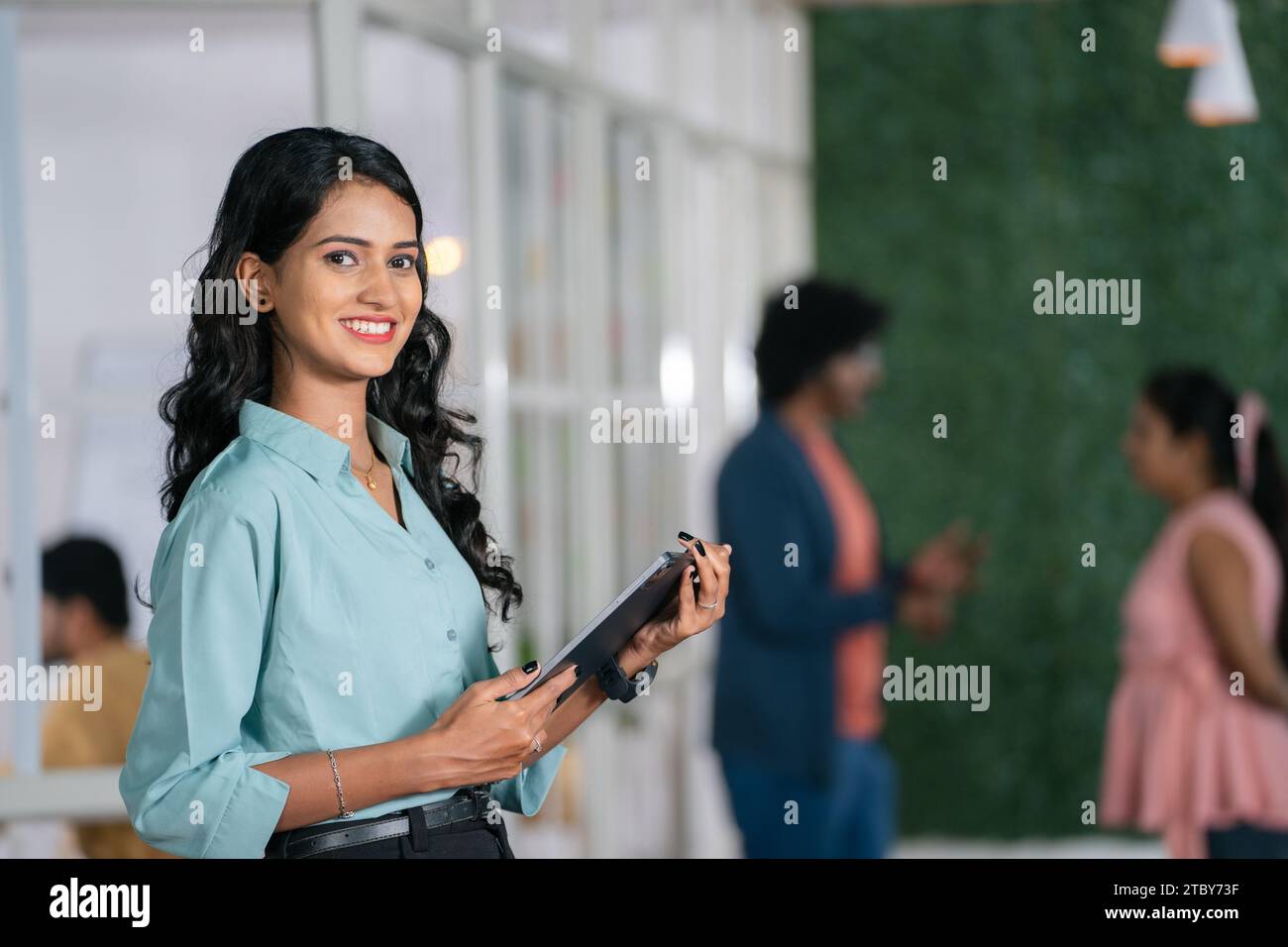 giovane donna dipendente sicura di sé che si trova in ufficio guardando la fotocamera con la scheda in mano - concetto di donna d'affari, imprenditrice di startup e carriera Foto Stock