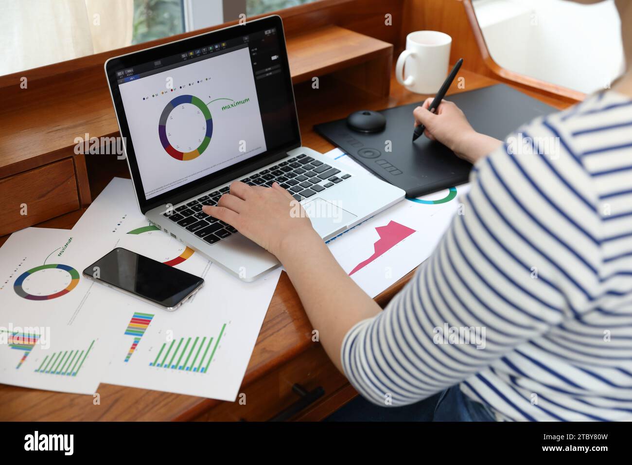 Donna che disegna grafici e grafici utilizzando tablet e notebook Foto Stock