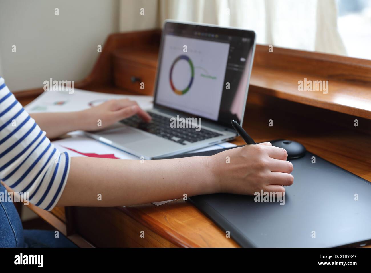 Donna che disegna grafici e grafici utilizzando tablet e notebook Foto Stock