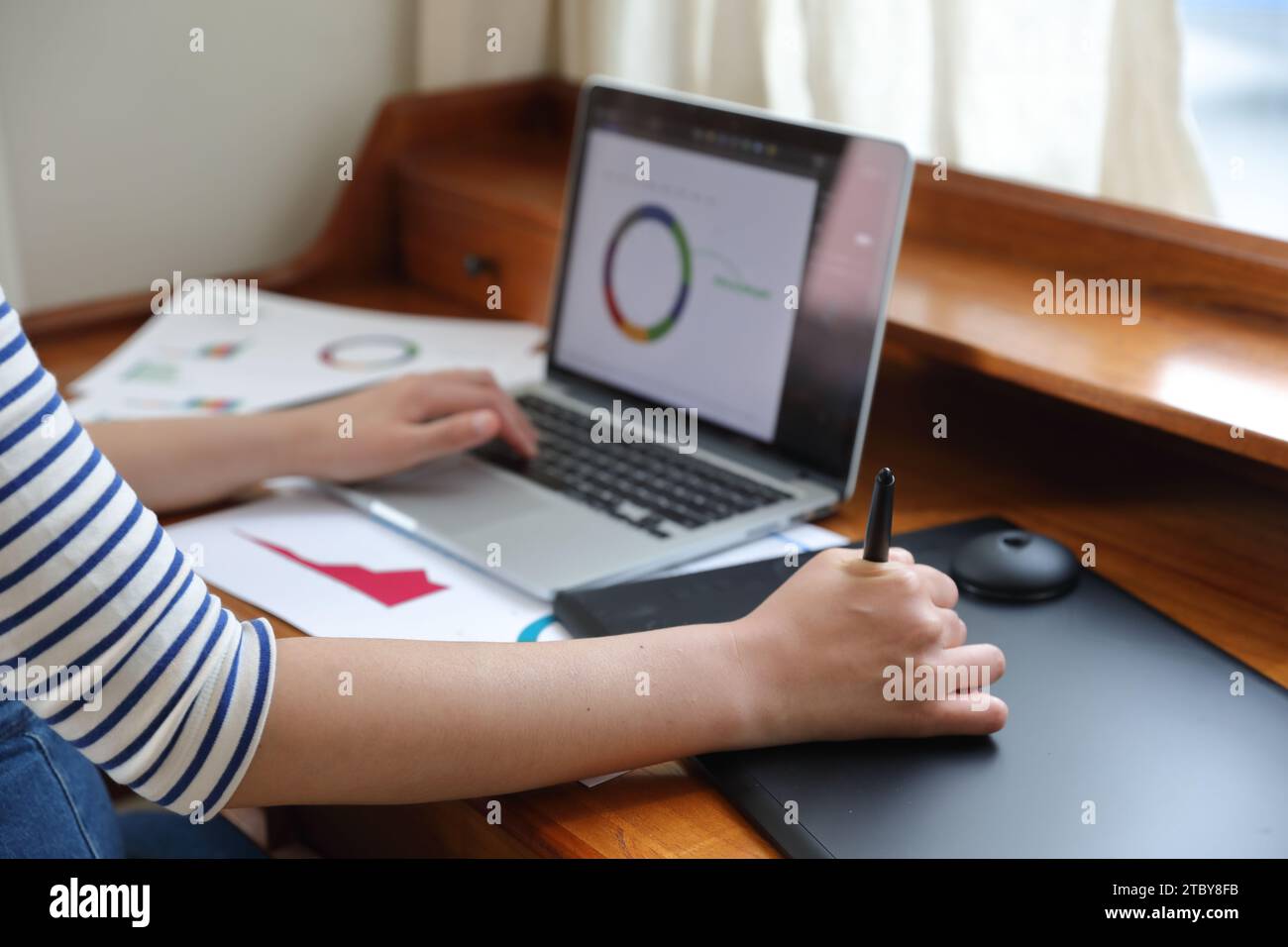 Donna che disegna grafici e grafici utilizzando tablet e notebook Foto Stock