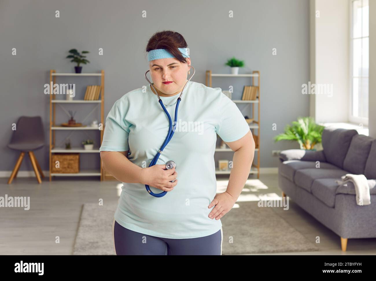 Donna grassa con stetoscopio sulla pancia che ascolta i suoni intestinali causati da problemi di digestione Foto Stock