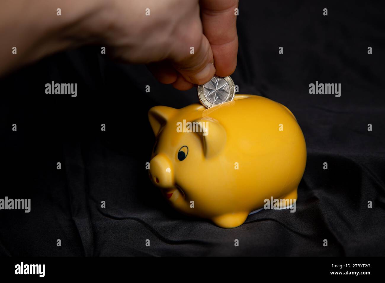 Ein Euro in eine Sparschwein stecken Foto Stock