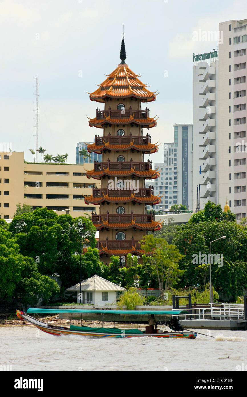 Bangkok, Thailandia - settembre 26 2011: Barca a coda lunga sul Chao Phraya con dietro, la pagoda di 9 piani presso la Jee Jin Foundation for the Moral Teach Foto Stock