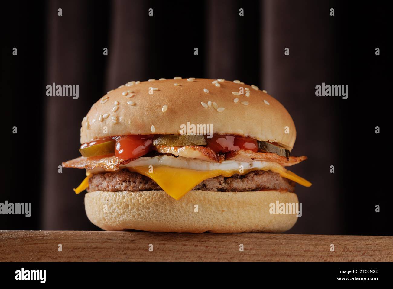 perfetto cheeseburger con pancetta saporita su un tavolo di legno su sfondo marrone Foto Stock