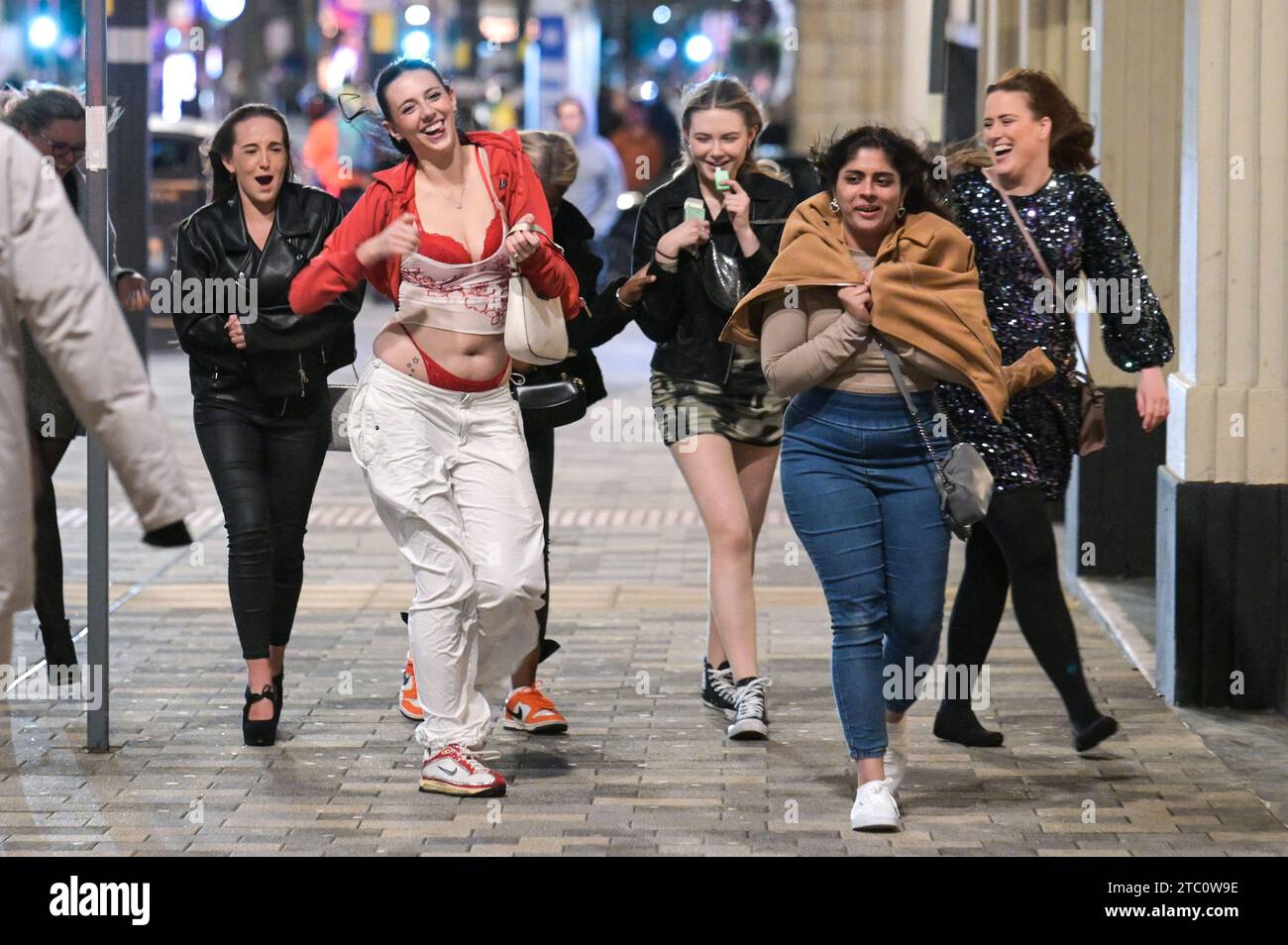 Broad Street, Birmingham 9 dicembre 2023 - i venditori hanno lottato per rimanere in posizione eretta sabato sera mentre raffiche di vento fino a 50 km/h colpivano Birmingham mentre Storm Elin colpiva la regione. I festaioli si sono rovinati i capelli, dato che gli edifici hanno creato un effetto tunnel del vento. La maggior parte indossava cappotti caldi e sciarpe, ma alcuni venivano fuori in abiti da festa, pronti a ballare tutta la notte, qualunque fosse il tempo all'aperto. I salti e i cappelli di Babbo Natale sono stati il tema della serata mentre la stagione delle feste di Natale è iniziata. Credito: Stop Press Media/Alamy Live News Foto Stock