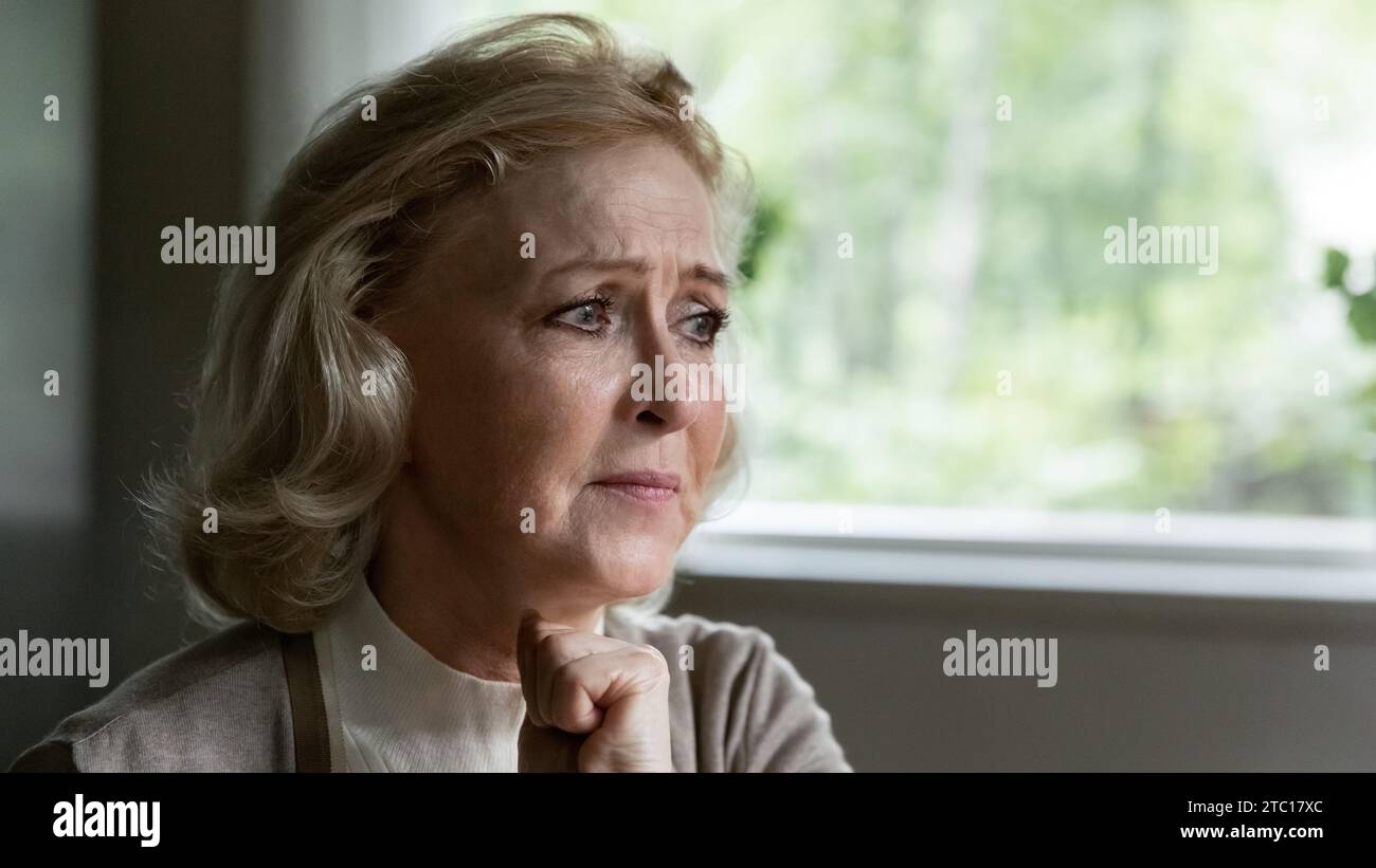 Una donna di mezza età turbata seduto alla finestra soffre di depressione Foto Stock