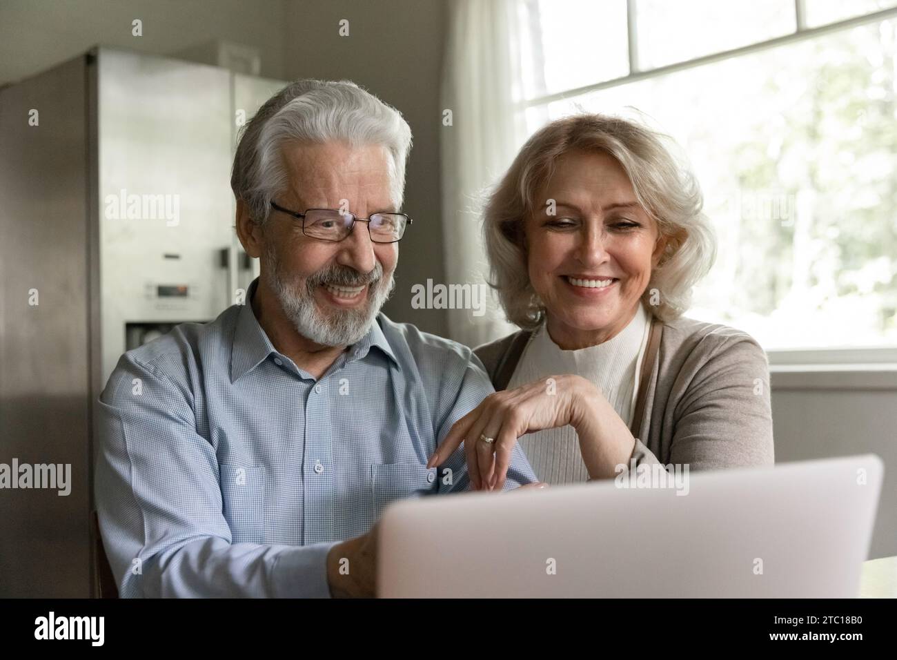 Gli amanti dei coniugi in pensione guardano un film comico sullo schermo del notebook Foto Stock