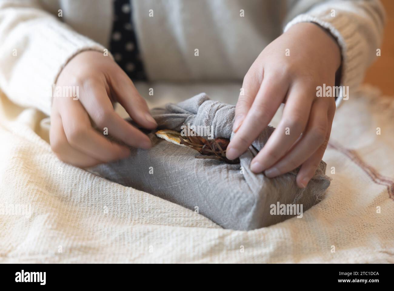una donna che tiene in mano un regalo al coperto, una confezione regalo ecologica, vista laterale Foto Stock