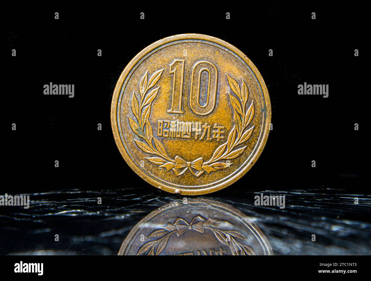 Un penny invecchiato seduto sopra un tavolo, con 10 Yen - Heisei, moneta giapponese Foto Stock