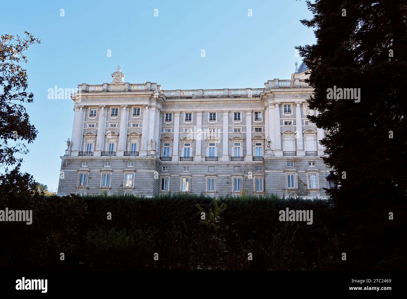 Il lato del Palacio Real a Madrid in una giornata senza nuvole in autunno, incorniciato da siepi Foto Stock