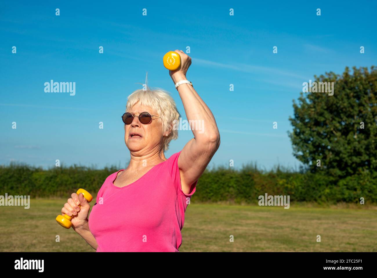 Donna anziana che usa pesi manubri per tenersi in forma Foto Stock